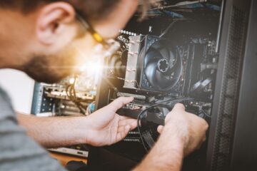 Technicien réparant l’intérieur d’un ordinateur pro reconditionné, vérifiant les composants et les câbles